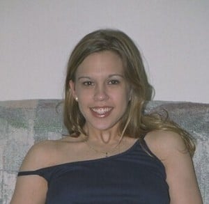 She is a stunning woman, sitting on the sofa.