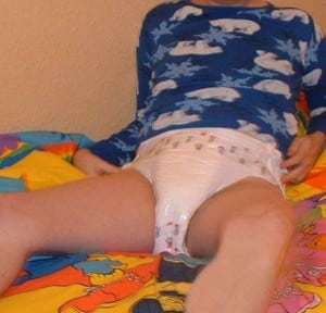 A Boy Infant He is diapered and seated on the bed.