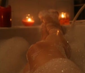 A bubble bath with candles She is seated in the bathtub and looks quite seductive.