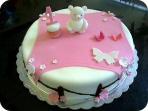 A beautiful cake with pink and white icing and a teddy bear appears.