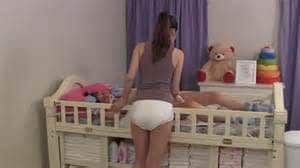 The boy is lying in the baby bed, and a naughty mother is standing next to it.