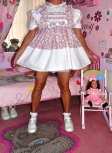Standing and donning the pink seductive gown is an adult baby.