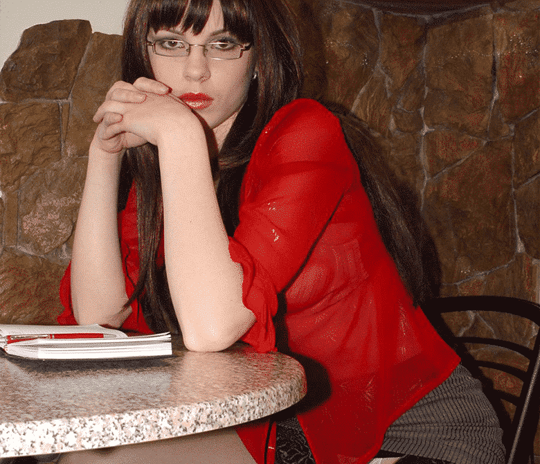 A woman dressed in crimson who is a terror is seated in the chair.
