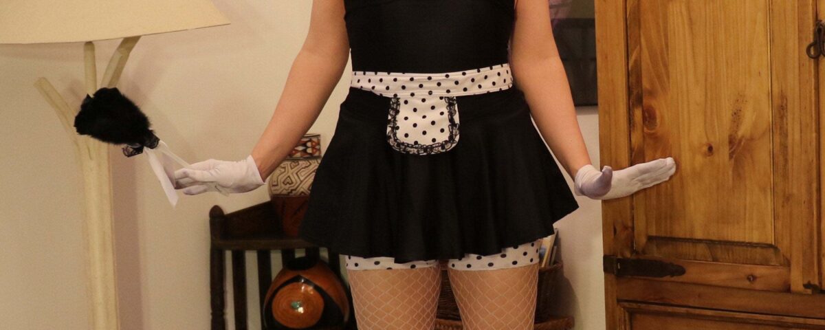 Standing in front of the photo session is a Sissy Training woman wearing the black attire.
